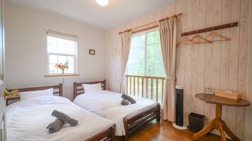 A room with two beds, a small table, and a window with curtains.