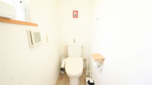 A small, compact bathroom with a toilet, a shelf with toiletries, and a wall-mounted air purifier. - Yatsugatake Angel AG1 (Hokuto)