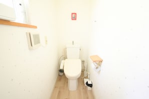 A small, compact bathroom with a toilet, a shelf with toiletries, and a wall-mounted air purifier. - Yatsugatake Angel AG1 (Hokuto)