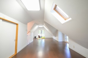 A spacious attic room with high ceilings, skylights, and a wooden floor.