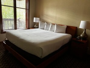 A hotel room with a large bed, two bedside tables with lamps, and a window with blinds. - Well appointed Ski-in Ski out cozy 1-bedroom condo walking distance from slopes. (Olympic Valley)