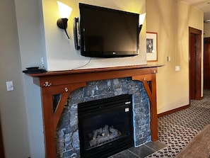 A fireplace with a stone surround and a flat-screen TV mounted above it.