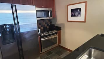 A kitchen with a stainless steel refrigerator, a microwave, an oven, and a sink.