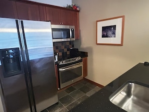 A kitchen with a stainless steel refrigerator, a microwave, an oven, and a sink.