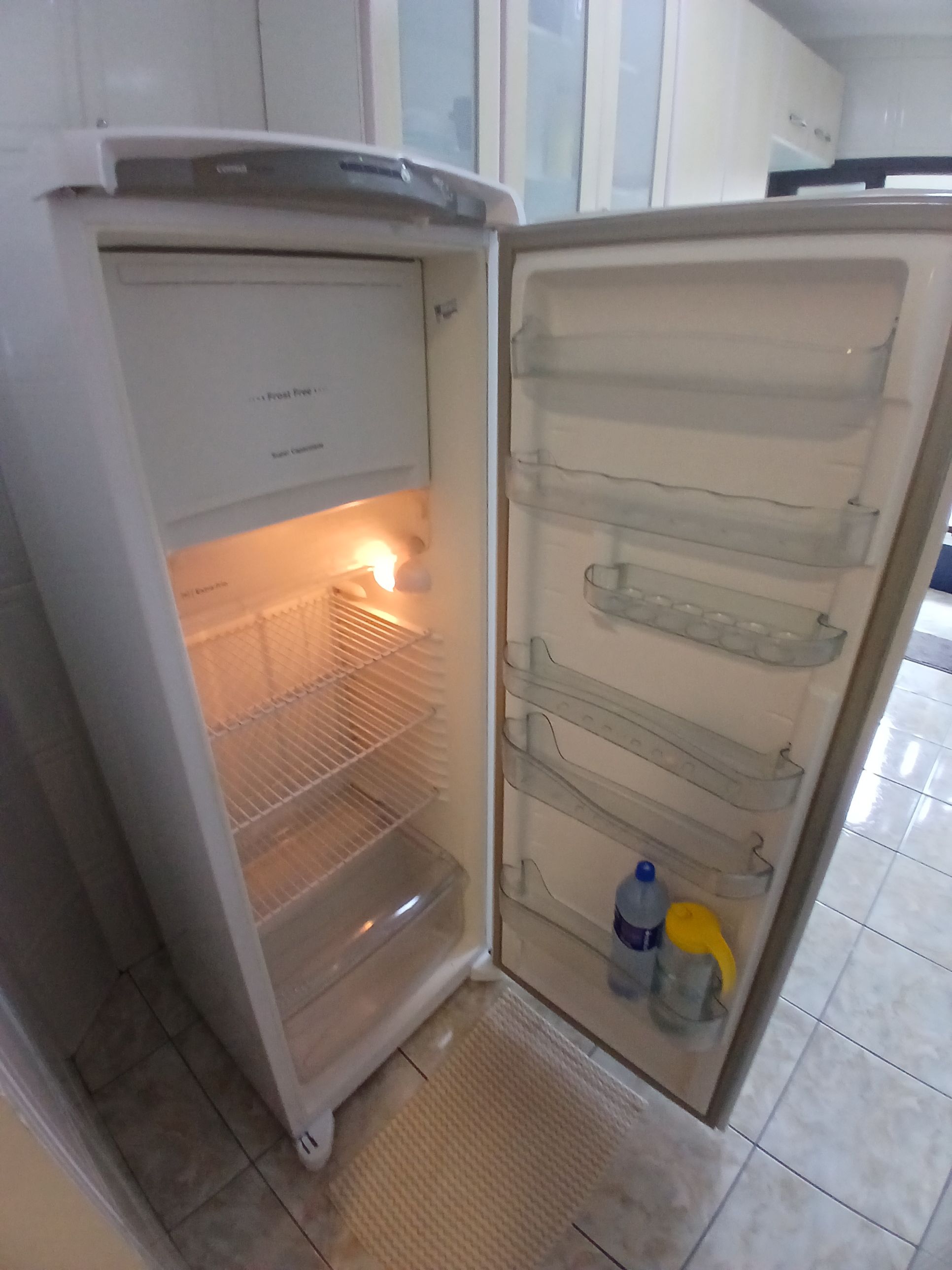Un refrigerador abierto con repisas y dispensador de agua.