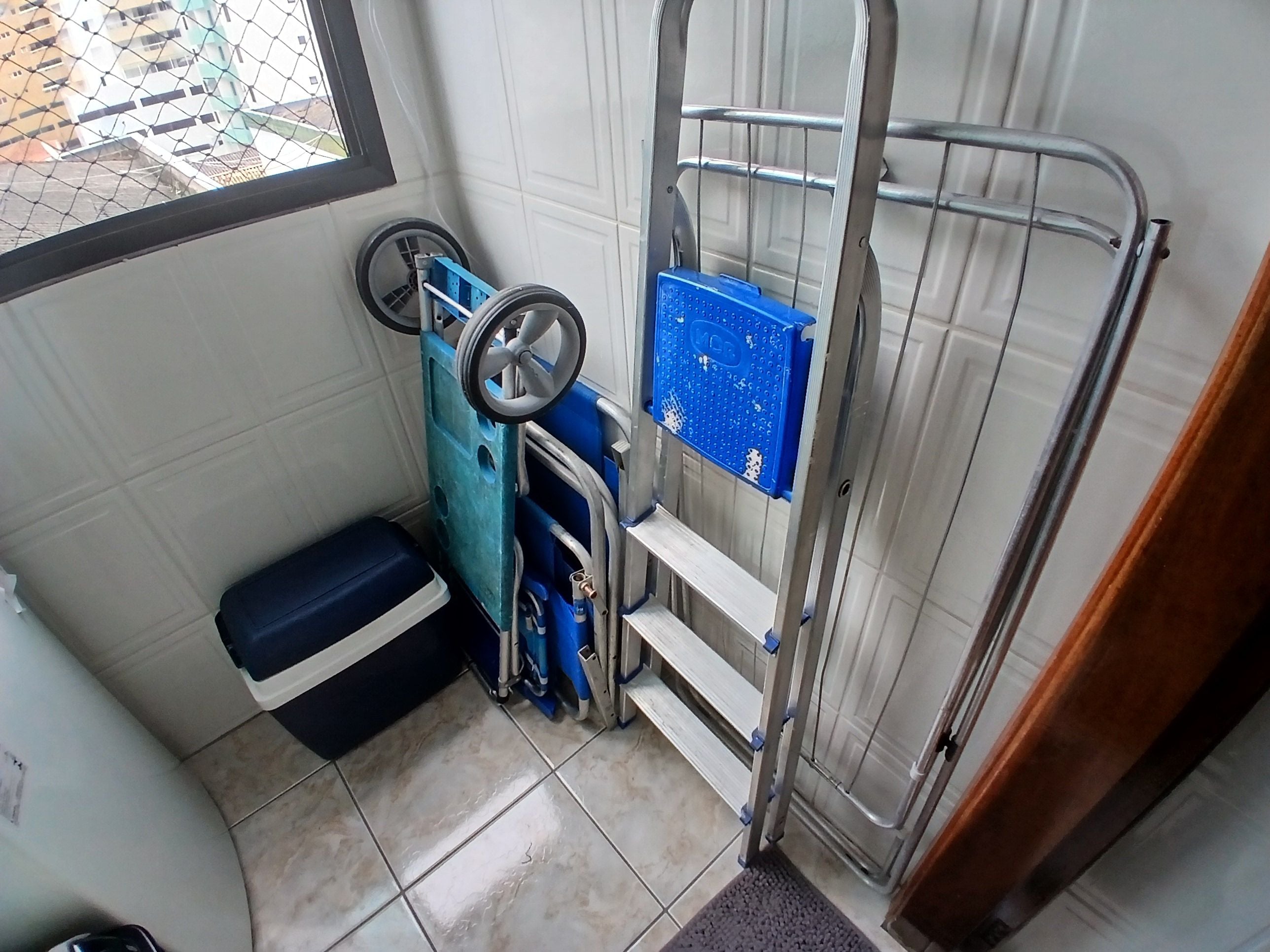Casa de banho compacta com cabine de duche, um móvel de armazenamento azul e um pequeno banco.
