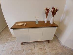 A reception desk with a wooden top, a white cabinet, and a tiled floor. - SHB 1 min praia - Família - Aconchegante (Praia Grande)