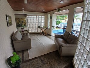 A hotel lobby with two sofas, a coffee table, a potted plant, and a view of the outside. - SHB 1 min praia - Família - Aconchegante (Praia Grande)