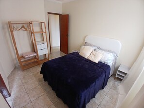 A bedroom with a bed, a wooden wardrobe, and a door. - SHB 1 min praia - Família - Aconchegante (Praia Grande)