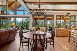 A spacious dining area with a round table and chairs, a chandelier, and a view of mountains through large windows. - Fall Escape Special: 15% Discount Ends Nov 30! Must book by Oct 18 (Pagosa Springs)