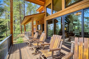 A wooden deck with outdoor seating and large windows overlooking a forested area. - Fall Escape Special: 15% Discount Ends Nov 30! Must book by Oct 18 (Pagosa Springs)