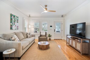 A living room with a sofa, coffee table, TV, and a ceiling fan. - NEW LISTING! The Swan on Park: Historic Charm near Lake Hollingsworth & FSC (Lakeland)