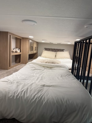 Ein Schlafzimmer mit einem Bett, einem Holzschrank und eingebauten Regalen.