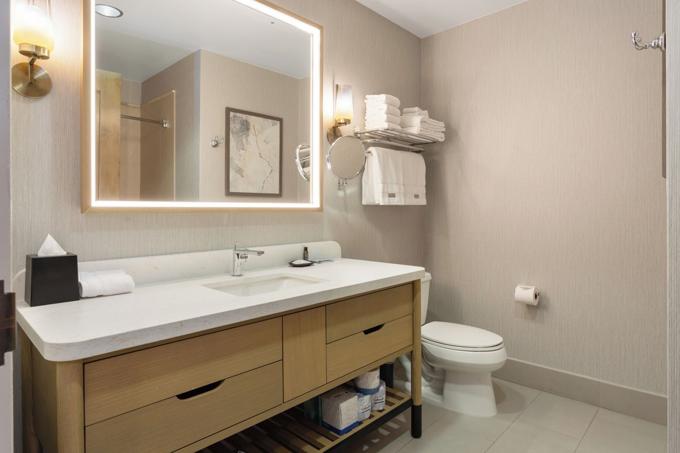 Une salle de bain moderne avec un lavabo blanc, un meuble-lavabo en bois, des toilettes et un porte-serviettes.