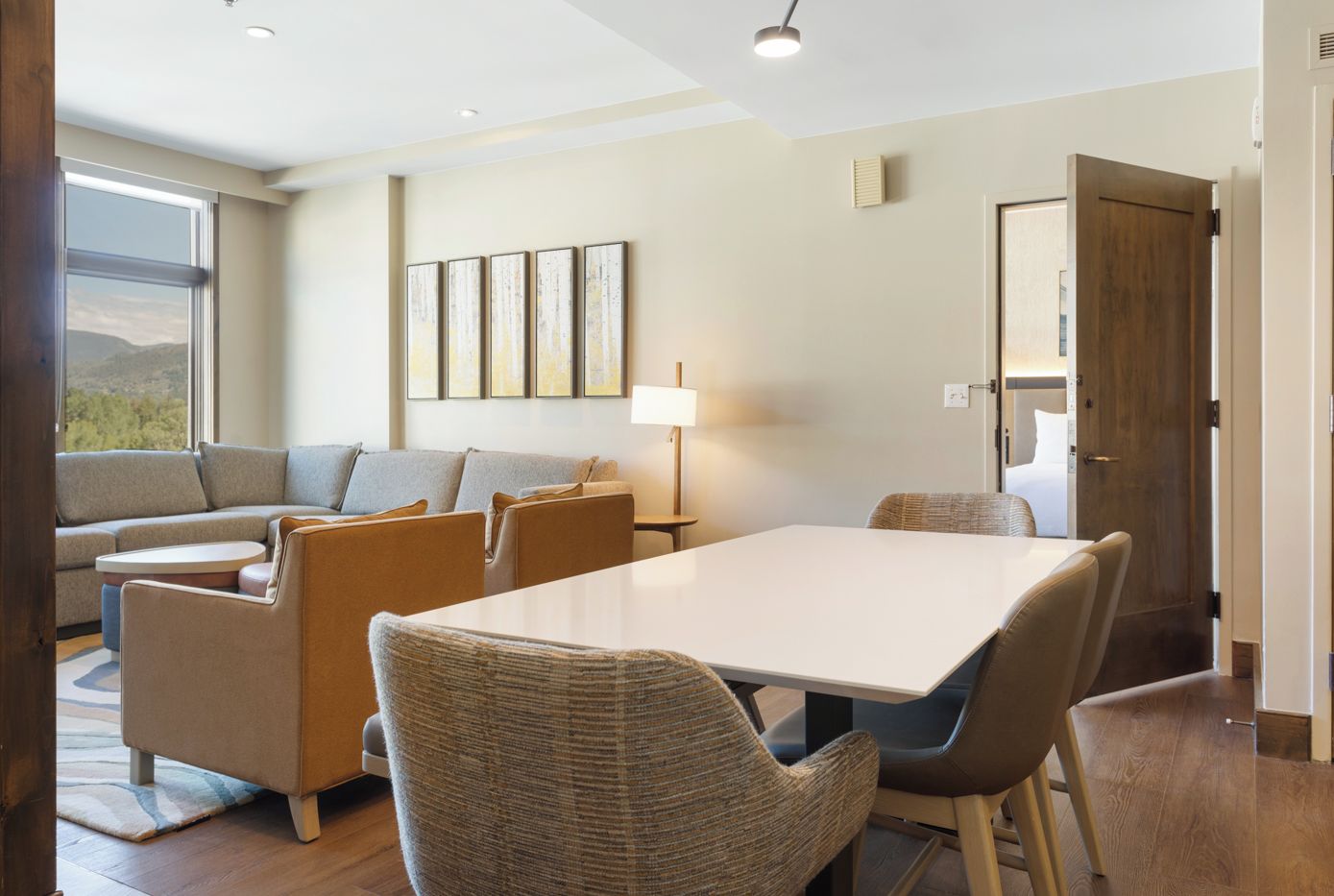Una sala de estar moderna con un sofá, sillas, una mesa de comedor y un amplio ventanal.