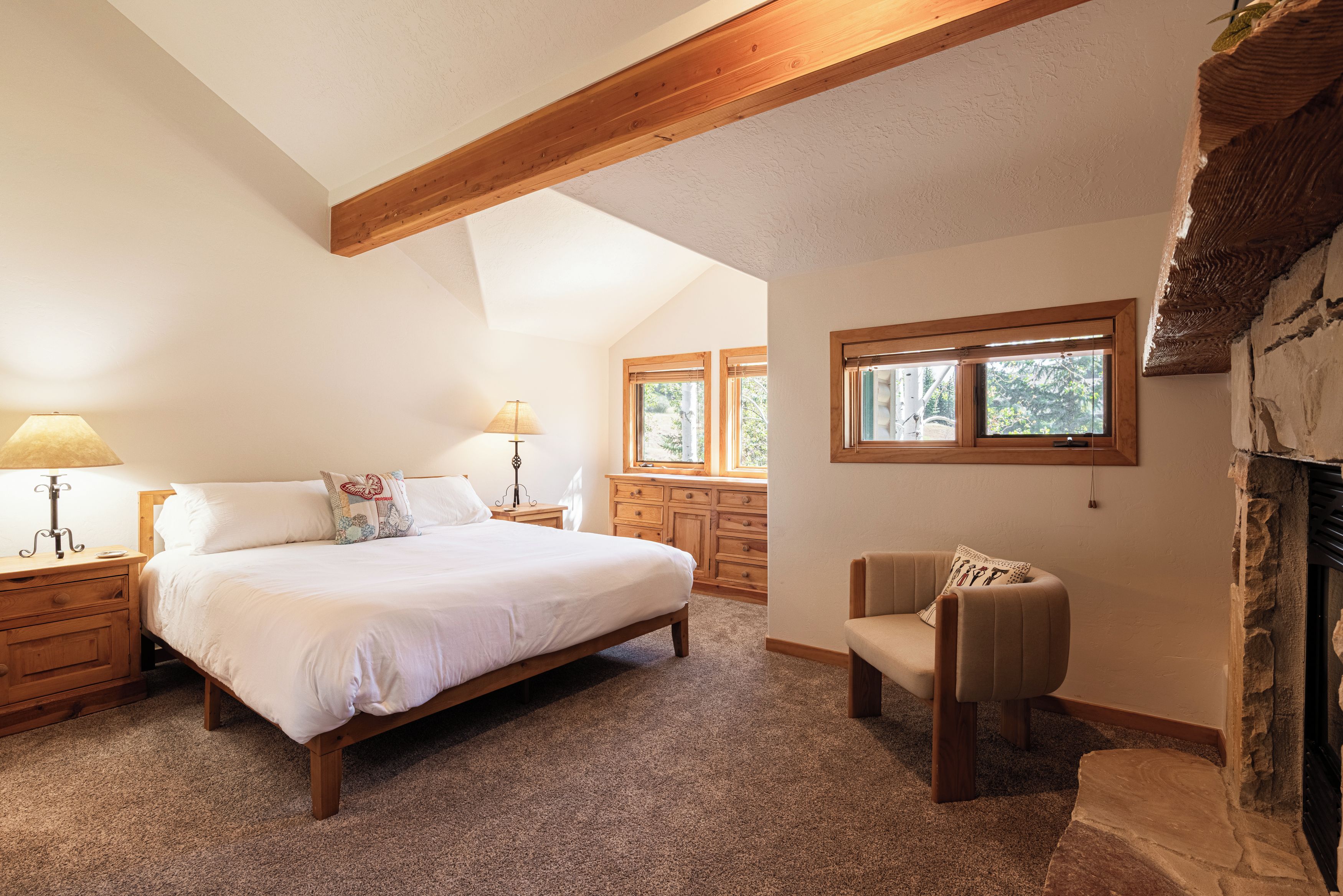 A bedroom with a bed, two bedside tables, a chair, and a window.