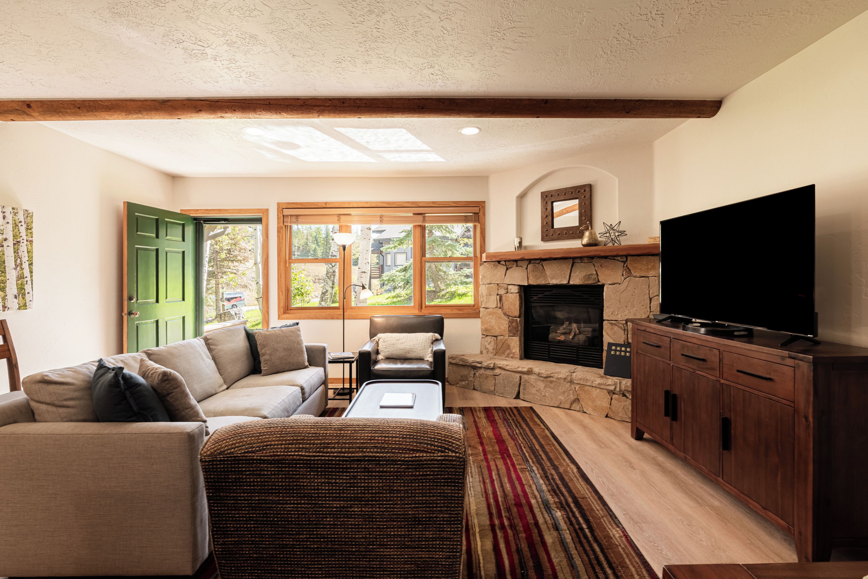 A living room with a stone fireplace, a television, and a sofa.