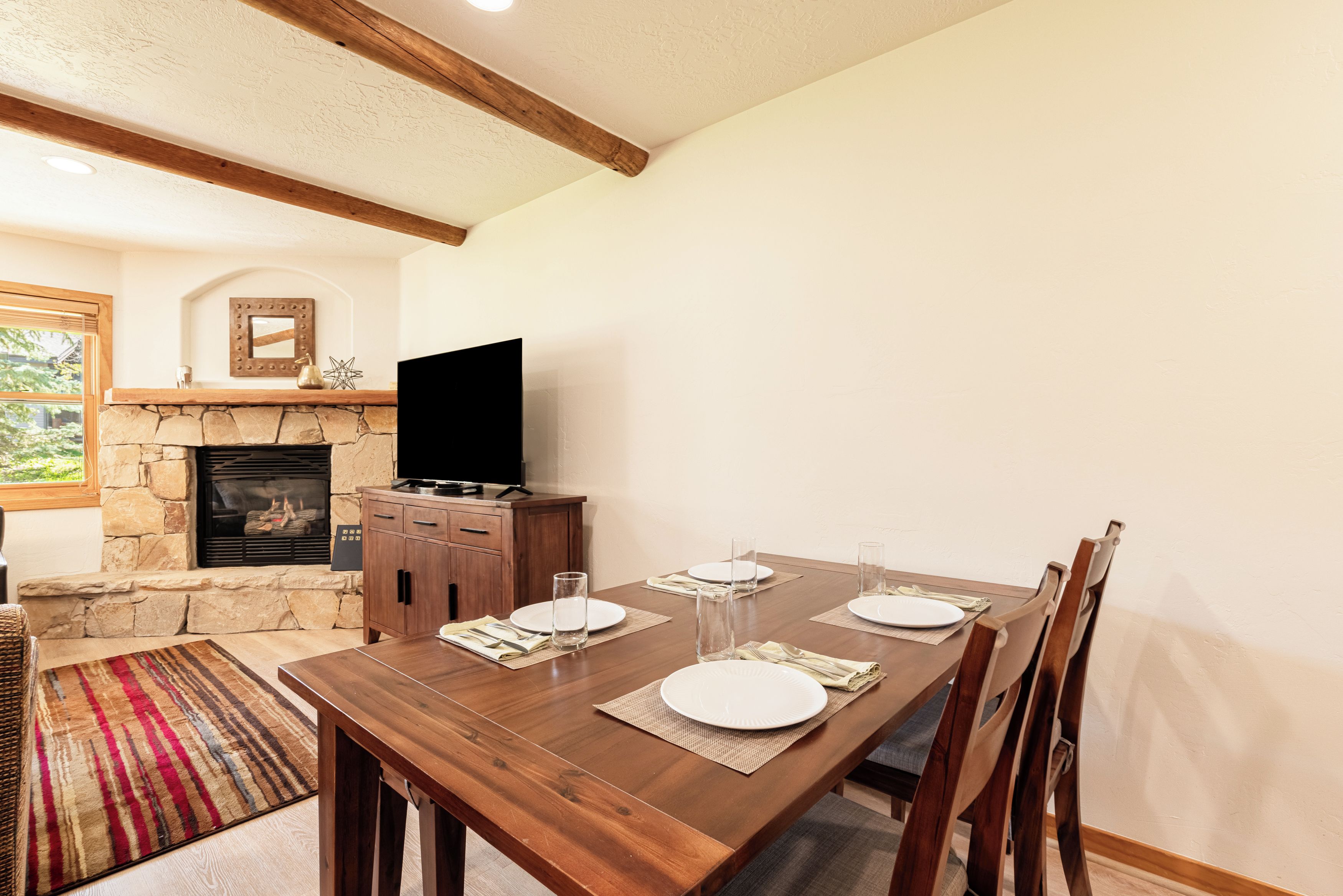 Uma sala de jantar com lareira de pedra, mesa de madeira e cadeiras.