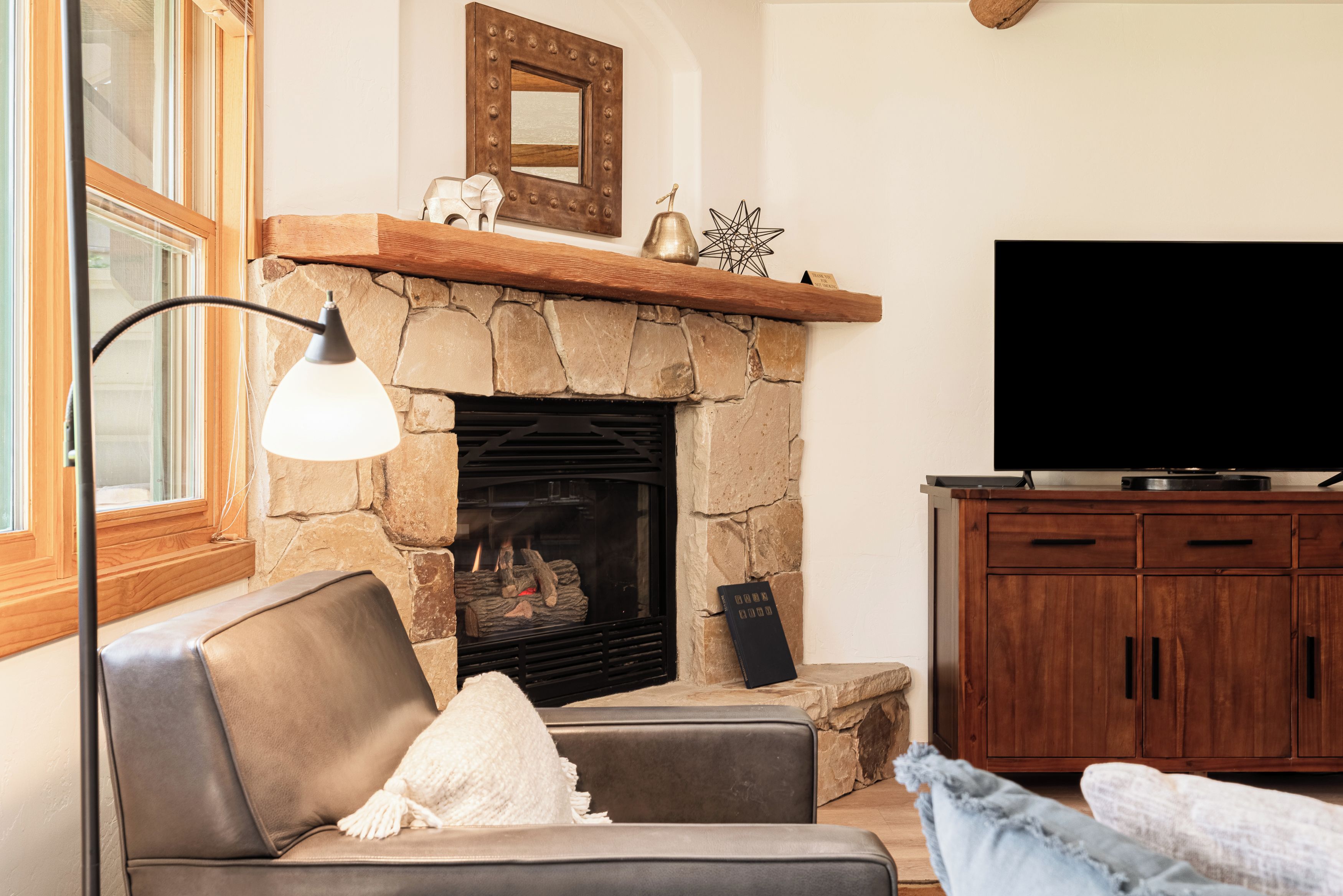 A living room with a stone fireplace, a television, and a sofa.