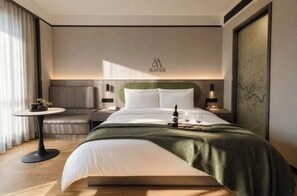 A modern hotel room with a large bed, a bedside table, a small table with a bottle and glasses, and a map on the wall. - MAUDE HOTEL NANNING (Nanning)
