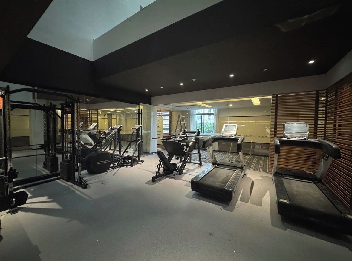 A gym with various exercise equipment including treadmills, a squat rack, and free weights.