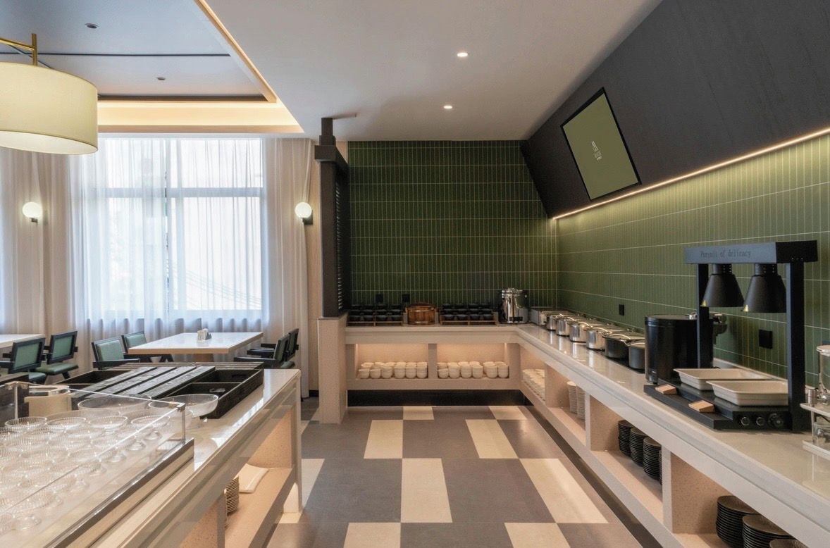 Una cocina moderna con piso a cuadros, una encimera amplia con diversos electrodomésticos y un rebozo de azulejos verdes.
