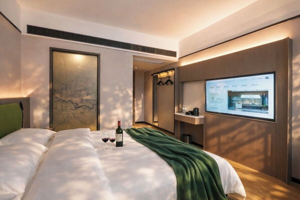 Habitació d'hotel moderna amb un llit gran, una obra d'art amb mapa, una televisió i un minibar.