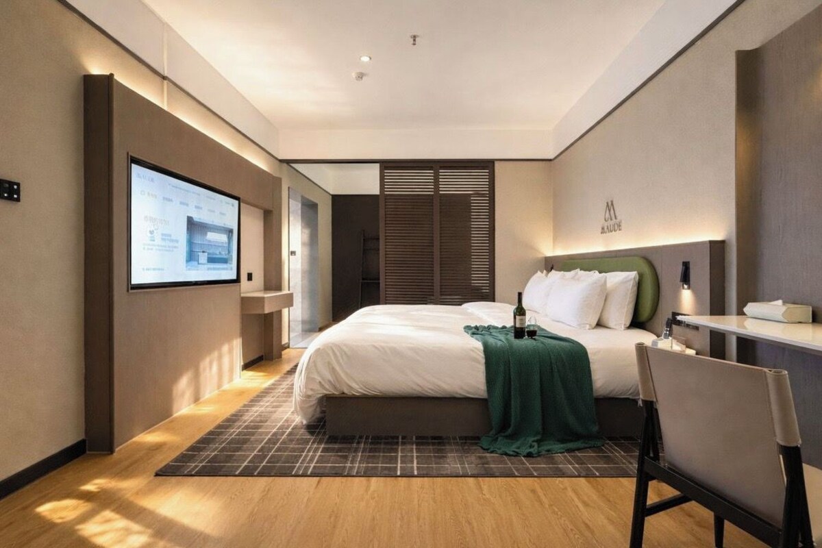Habitació d'hotel moderna amb un llit, un escriptori i una pantalla de televisió.