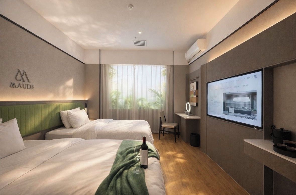 Una habitación de hotel con dos camas, un escritorio, un televisor y una ventana con cortinas.