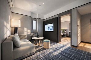 A modern hotel room with a sofa, a small round table, a lamp, and a TV screen. - MAUDE HOTEL NANNING (Nanning)