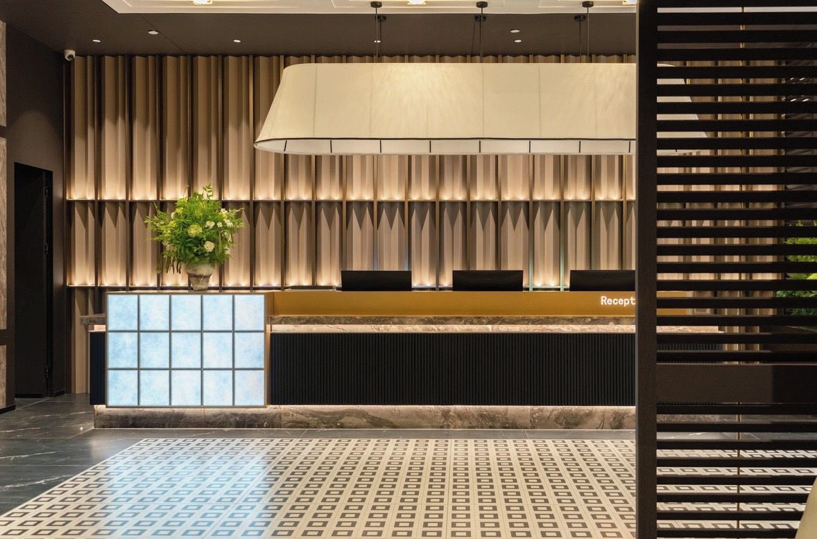A reception area with a reception desk, a large potted plant, and a patterned floor.