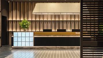 A reception area with a reception desk, a large potted plant, and a patterned floor.