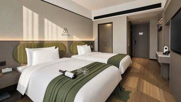 A hotel room with two beds, a minibar, a television, and a wall-mounted artwork.