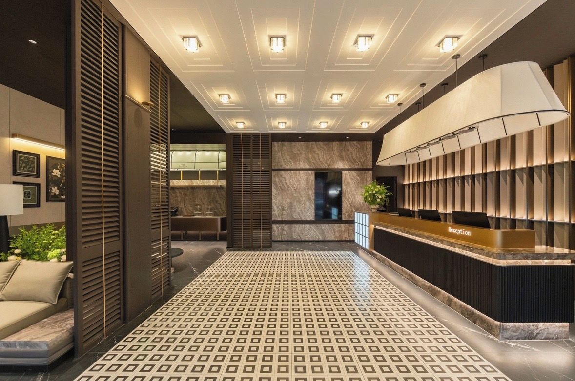 A hotel reception area with a reception desk, patterned floor, and ceiling lights.