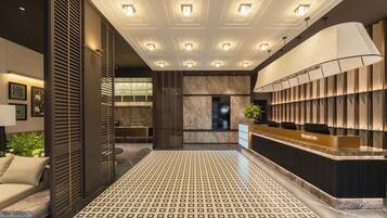 A hotel reception area with a reception desk, patterned floor, and ceiling lights.