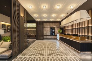 A hotel reception area with a reception desk, patterned floor, and ceiling lights. - MAUDE HOTEL NANNING (Nanning)
