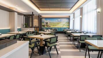 A restaurant with multiple tables and chairs, a mural on the wall, and large windows.
