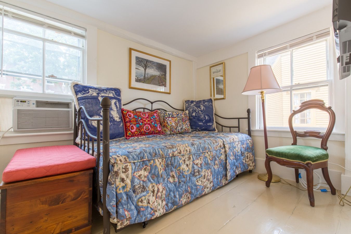A bedroom with a bed, a chair, a bedside table, and a window.