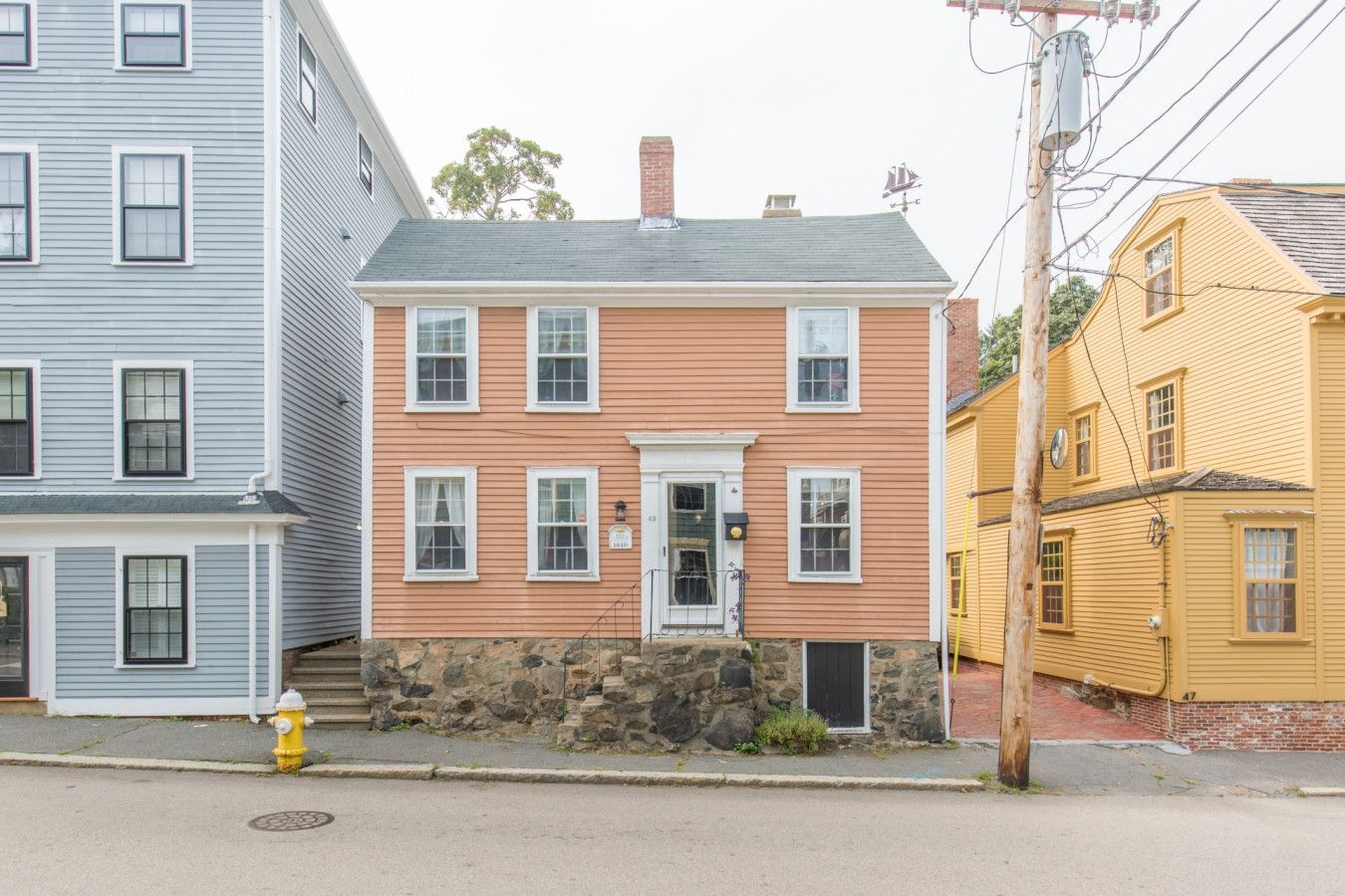 A two-story house with a stone foundation, a front door, and a small porch.