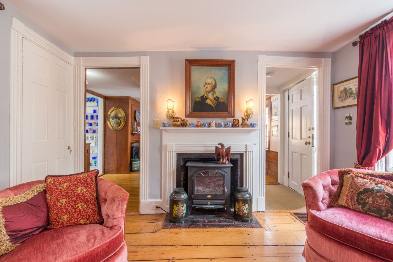 A living room with a fireplace, two red sofas, and a painting above the mantel.