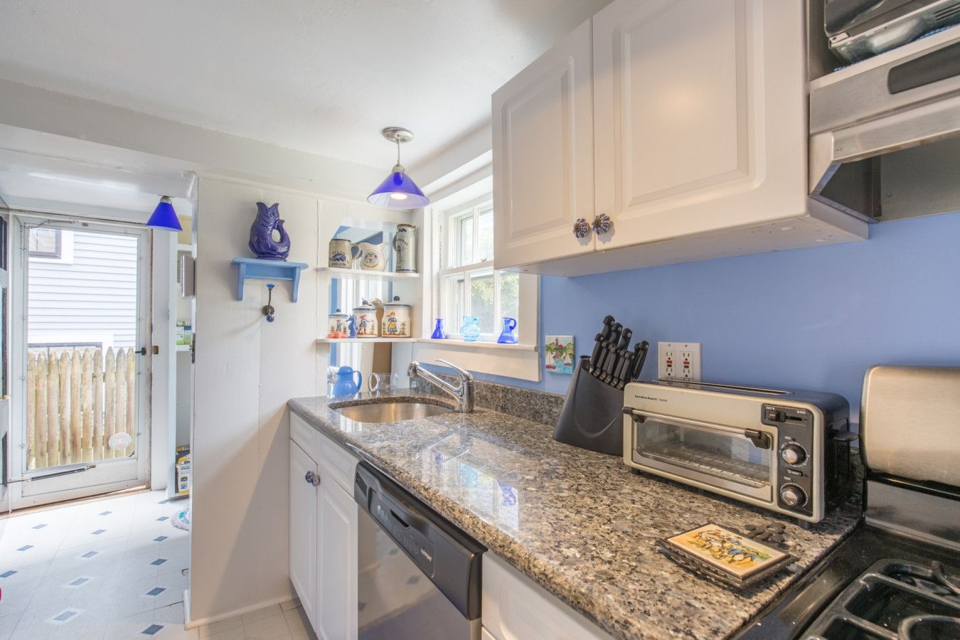 A kitchen with white cabinets, a granite countertop, a toaster, and a dishwasher.