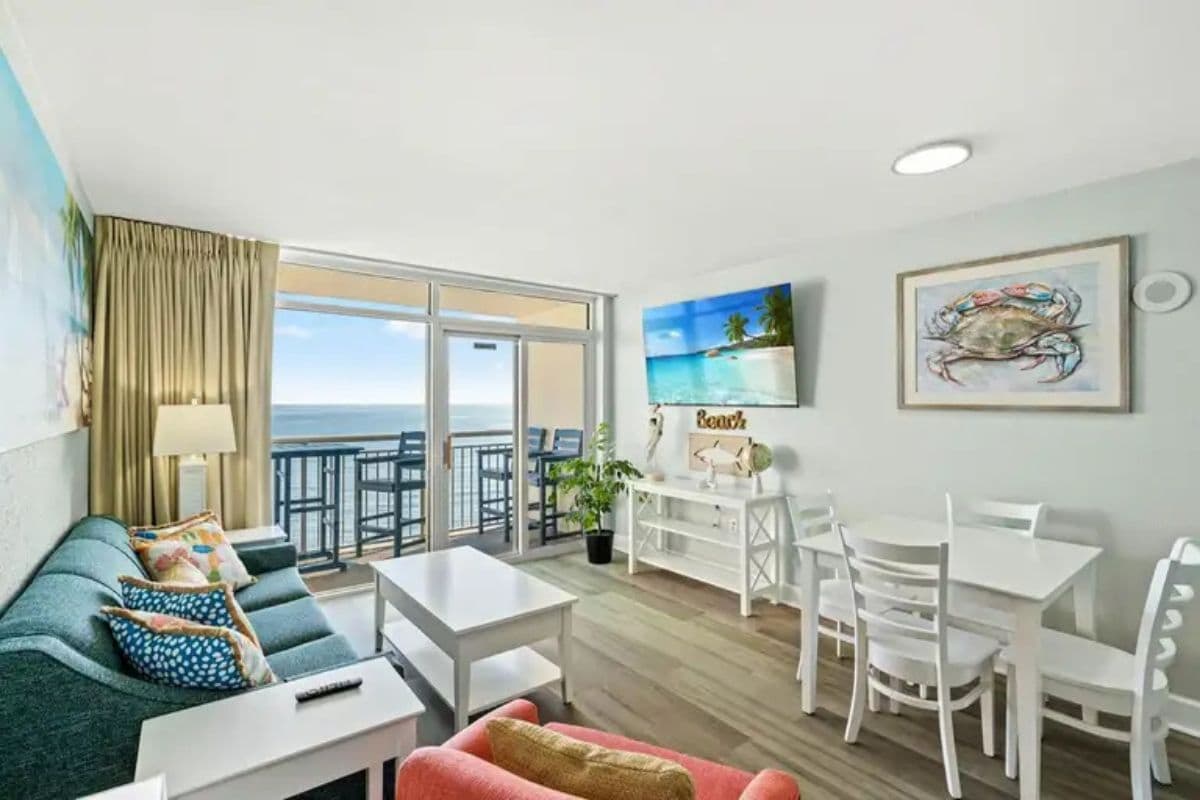 A room with a balcony, a dining area, and a sofa.
