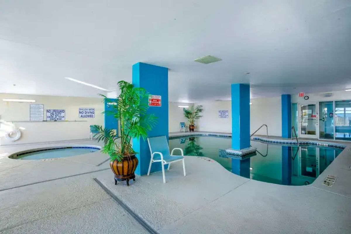 An indoor swimming pool with blue walls and a chair.
