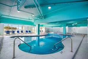 An indoor swimming pool with clear water, surrounded by lounge chairs and a tiled floor. - Luxury Oceanfront 1BR | Designer Decor (North Myrtle Beach)