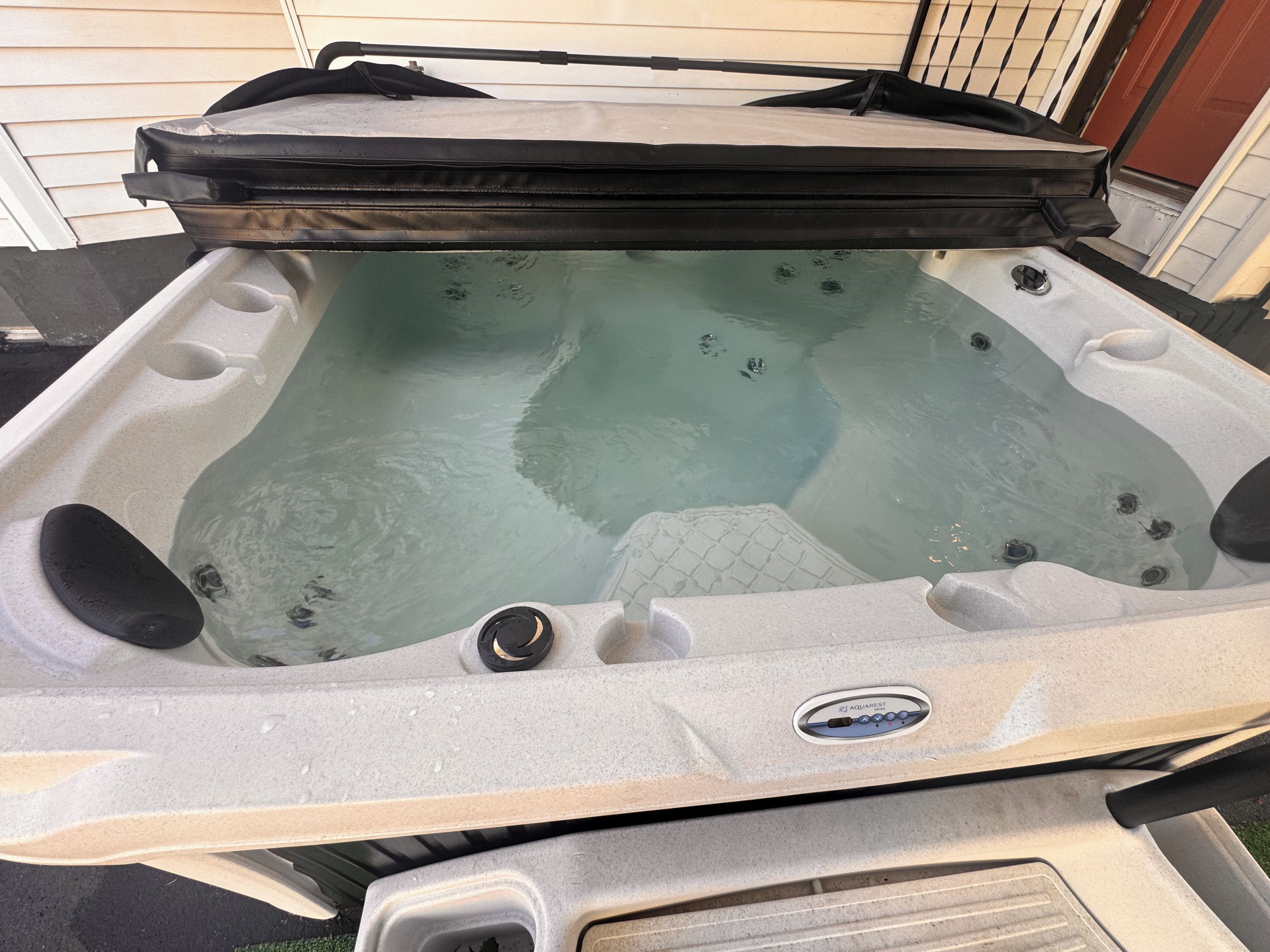 A hot tub with a control panel, a lid, and a water pump.