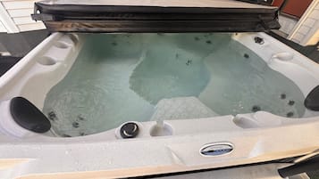 A hot tub with a control panel, a lid, and a water pump.