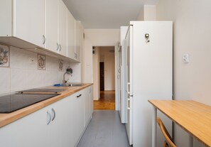 A narrow kitchen with white cabinets, a wooden countertop, and a built-in stove. - Warsaw Royal Route Apartment (Warszawa)