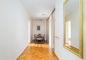 A hallway with a dining area, wooden flooring, and a large mirror. - Warsaw Royal Route Apartment (Warszawa)
