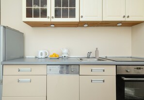 Een keuken met een roestvrijstalen koelkast, een koffiezetapparaat, een waterkoker, een spoelbak en een fornuis.