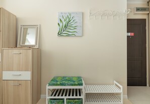 Ein Zimmer mit einem Holfischschrank, einem weißen Babybett mit einem blattgemusterten Matratze, einem an der Wand befestigten Bettgitter und einer Tür mit einem roten Schild.